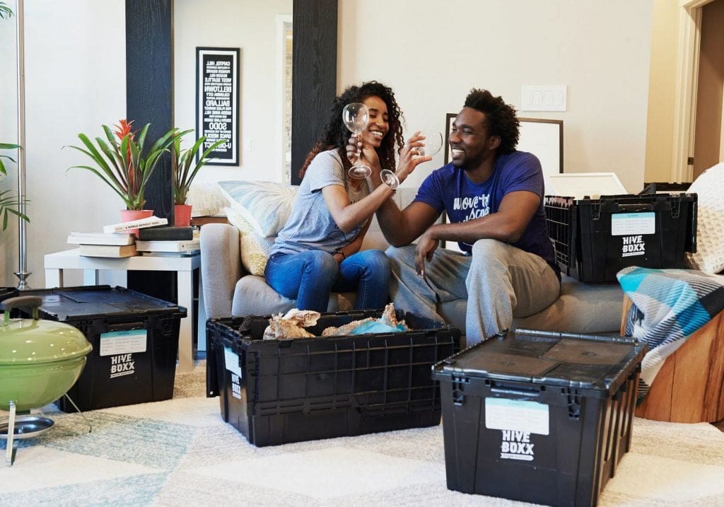 Young couple unpack moving boxes and celebrate by getting out the wine glasses first